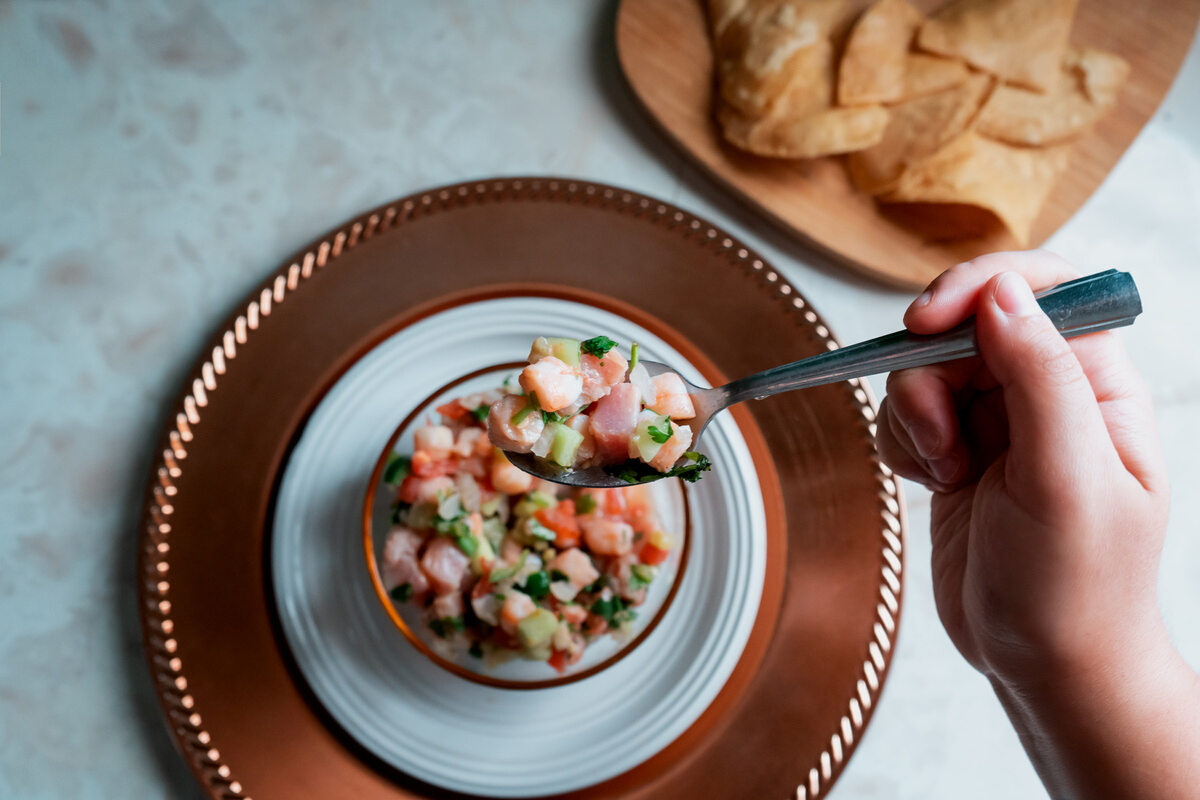 Hand Holding Spoonful of Ceviche